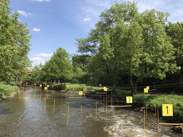 Die Trainingsstelle an einem sonnigen Tag mit einem Schild im Vordergrund. Darauf steht: Landesleistungsstützpunkt für Kanu-Slalom des Kanu-Verbandes NRW