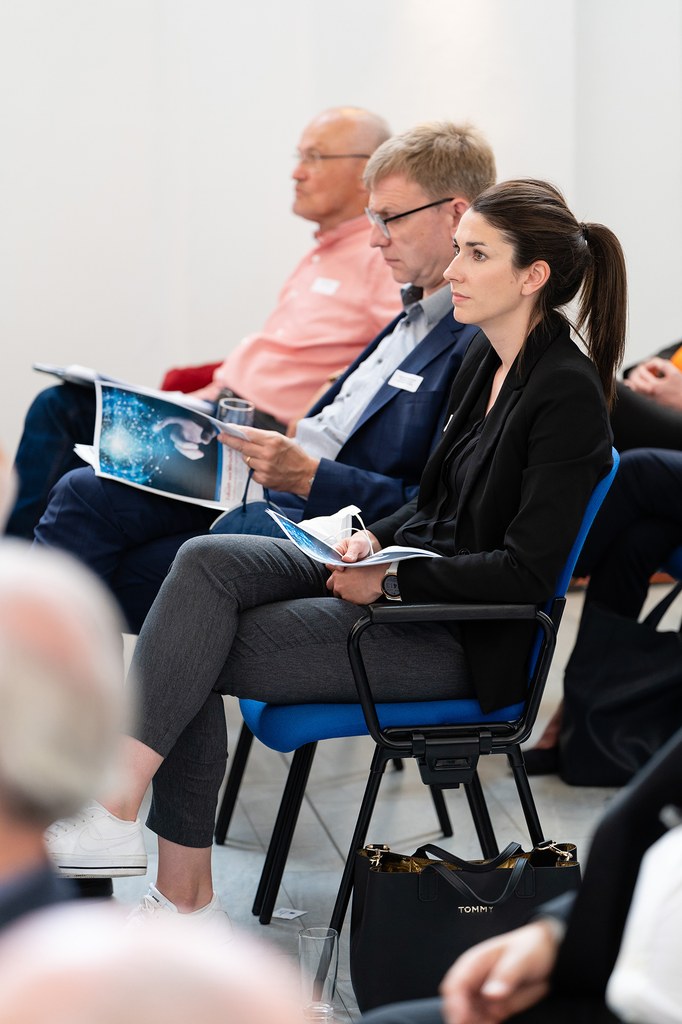 Konferenz-Teilnehmer*innen folgen einem Redebeitrag.